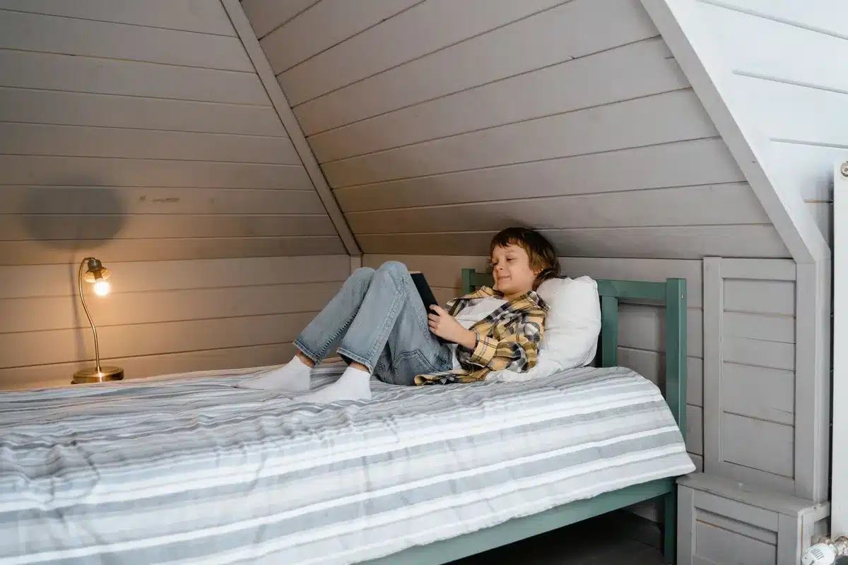 Coin sommeil avec lit bas, lampe douce et rangements accessibles pour un jeune enfant