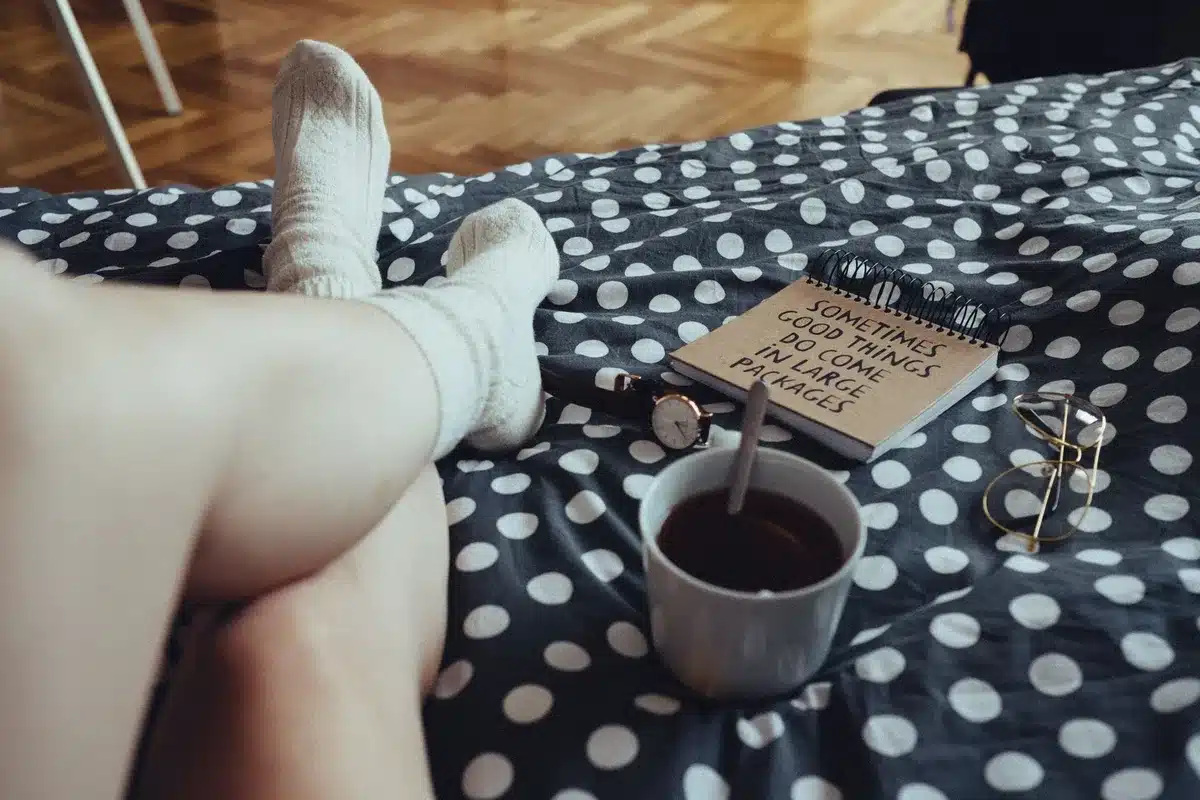 Personne écrivant dans un carnet avec une tasse de thé, moment de calme introspectif