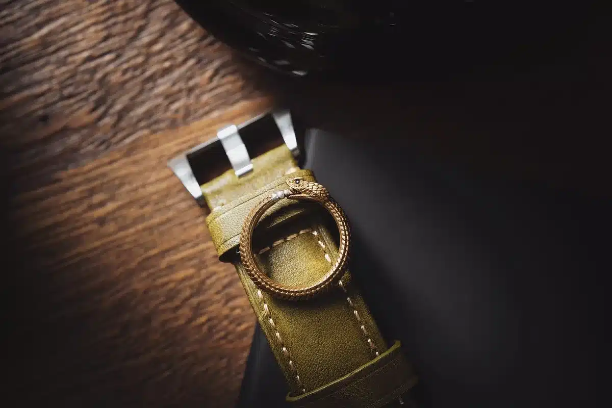 Détail d'accessoires mode : ceinture, bijoux et montre posés sur des vêtements