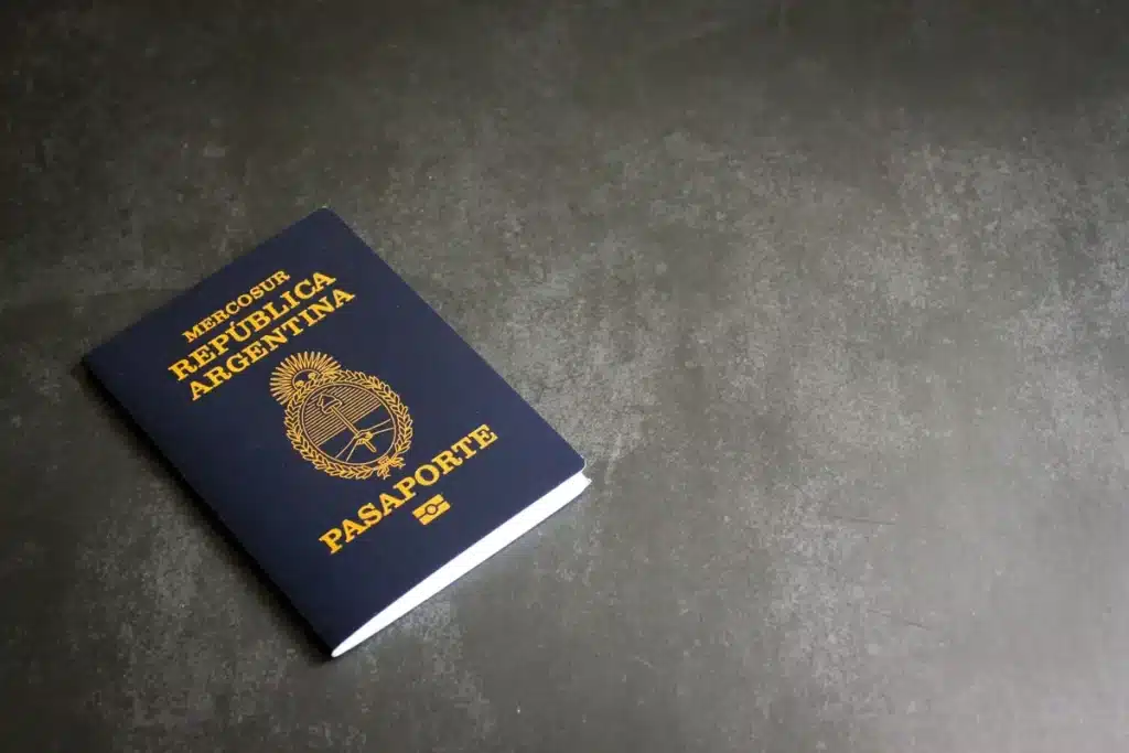 Mains tenant un passeport ouvert à côté d'un ordinateur portable affichant un formulaire de demande en ligne