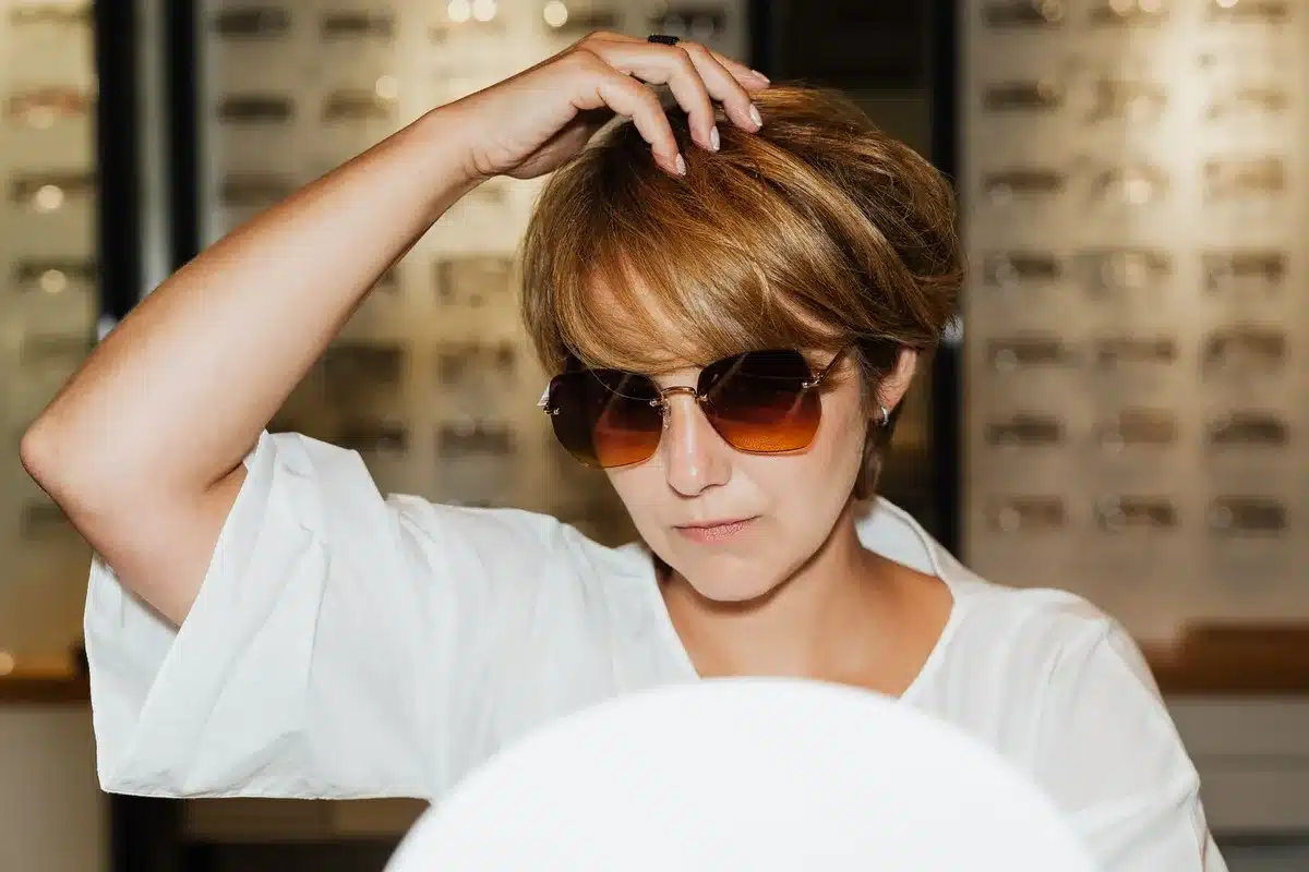 Femme essayant différentes tailles de lunettes oversize devant un miroir
