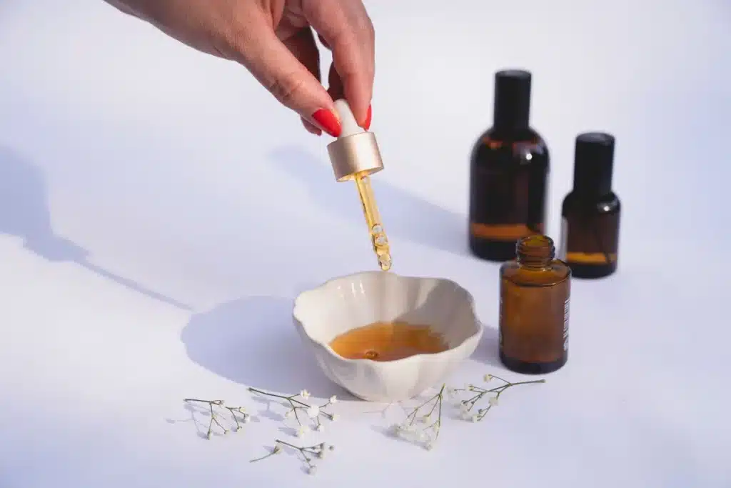 Mains appliquant un soin huileux sur la peau du visage, lumière naturelle douce