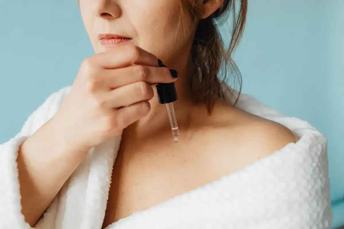 Application de quelques gouttes d'huile sur le visage avec la main