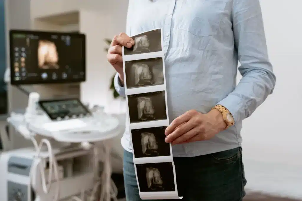 Femme enceinte en consultation médicale, main sur le ventre, environnement hospitalier