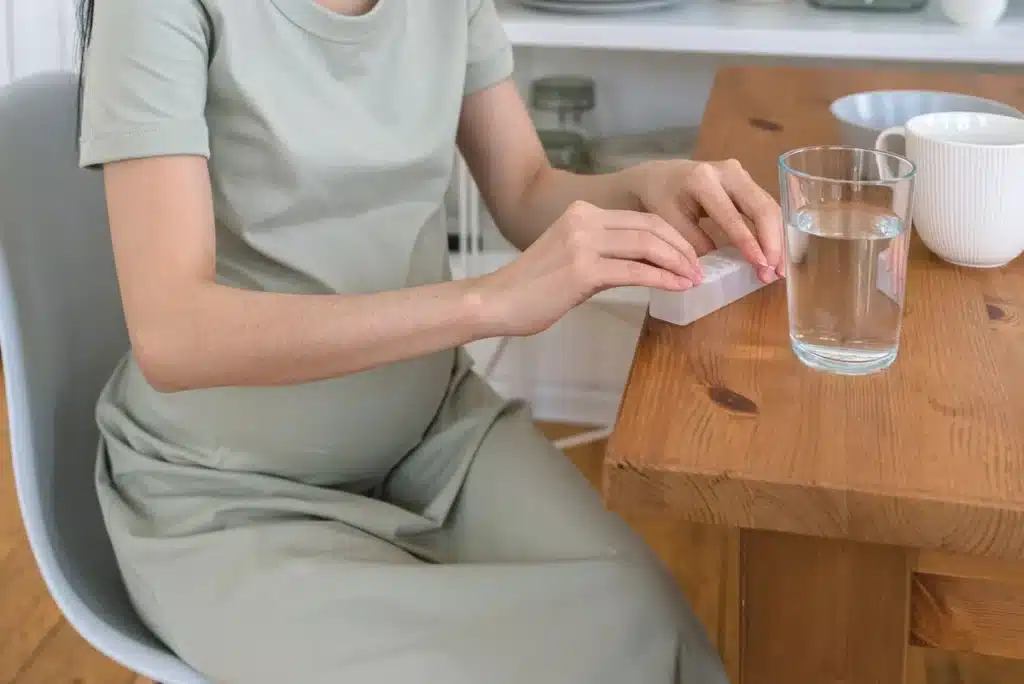 Femme enceinte sereine avec verre d'eau et aliments riches en magnésium