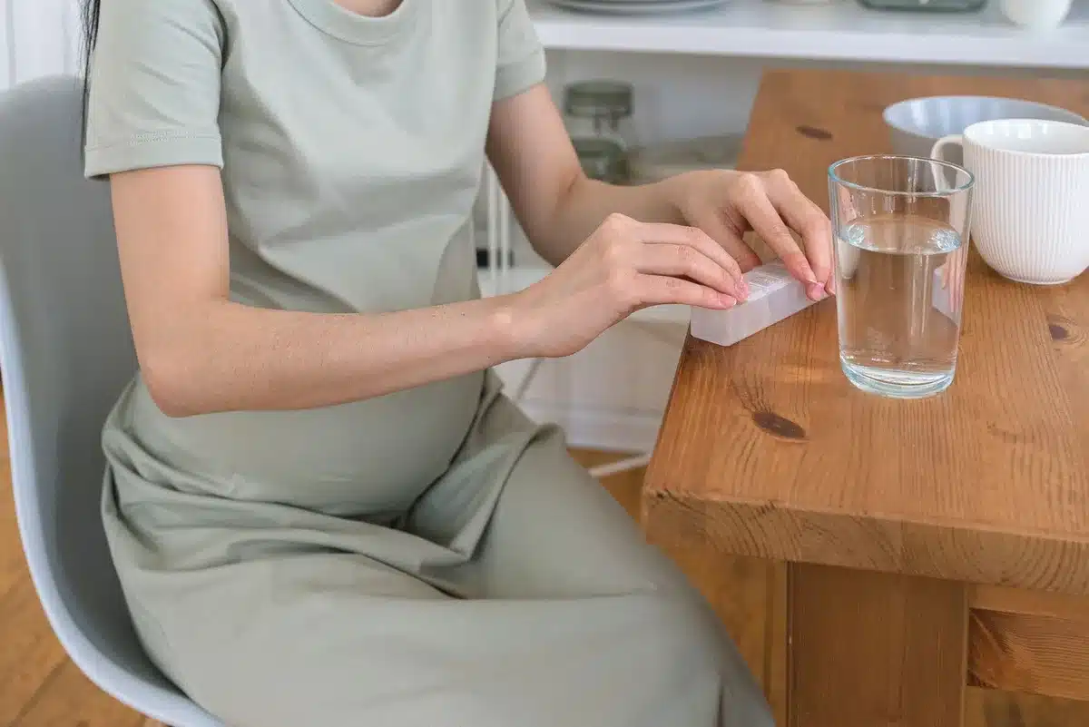 Femme enceinte sereine avec verre d'eau et aliments riches en magnésium