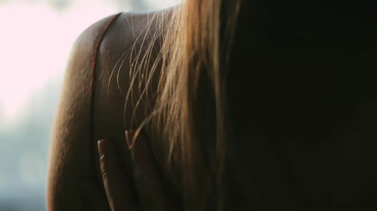 Silhouette d'une femme de dos, mains sur les hanches, dans une lumière douce.