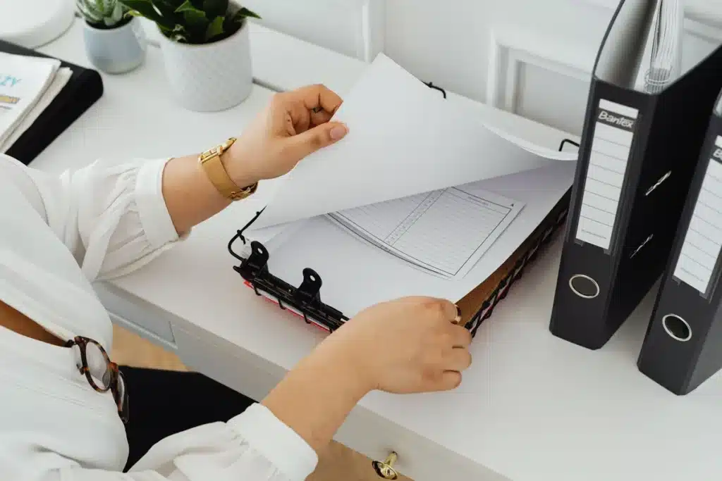 Mains tenant des documents administratifs vierges sur un bureau avec des papiers éparpillés