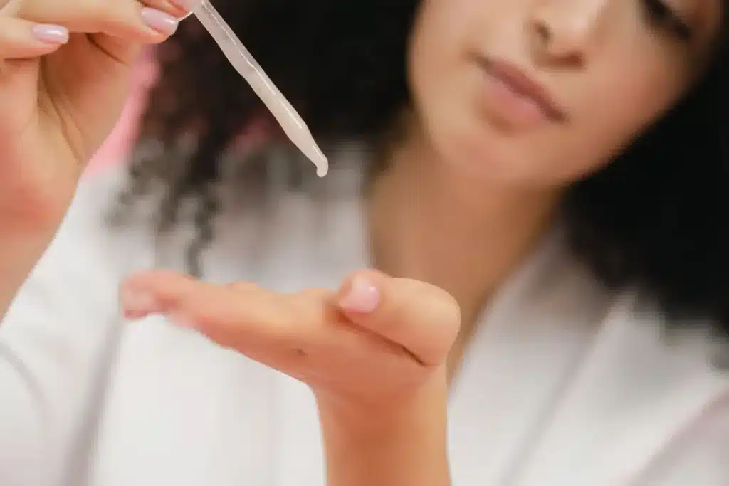 Mains appliquant délicatement un gommage visage sur la peau, mise en lumière douce