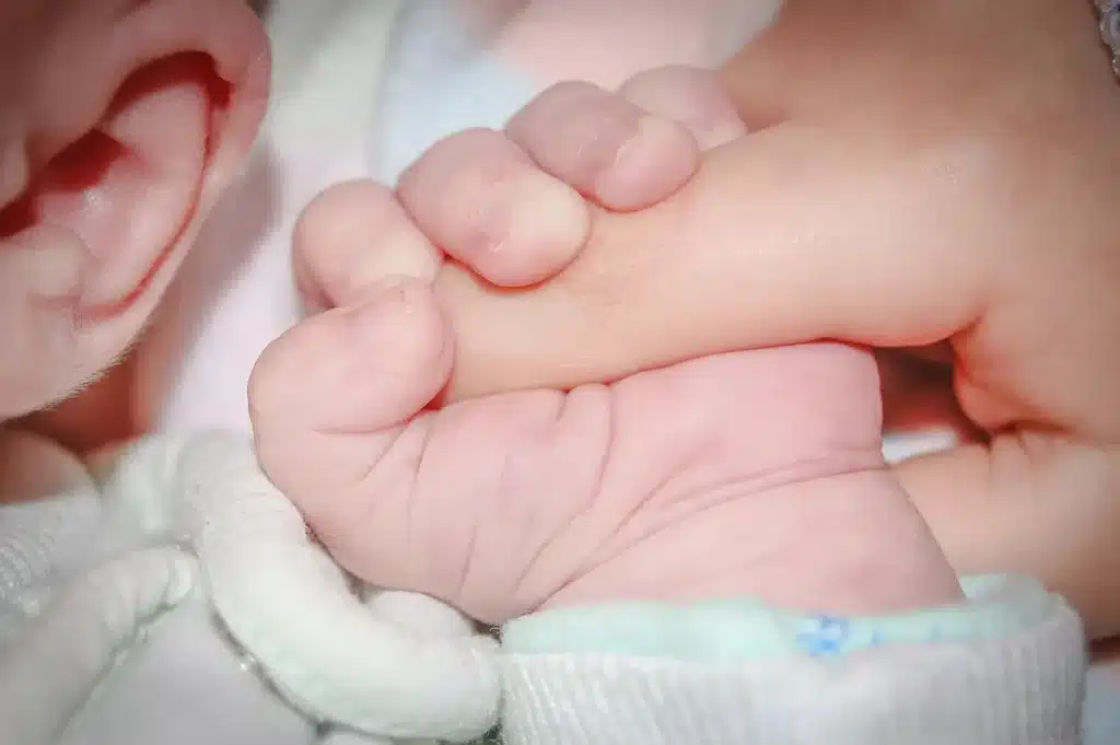 Mains appliquant délicatement un hydrolat sur la peau douce d'un bébé avec un coton