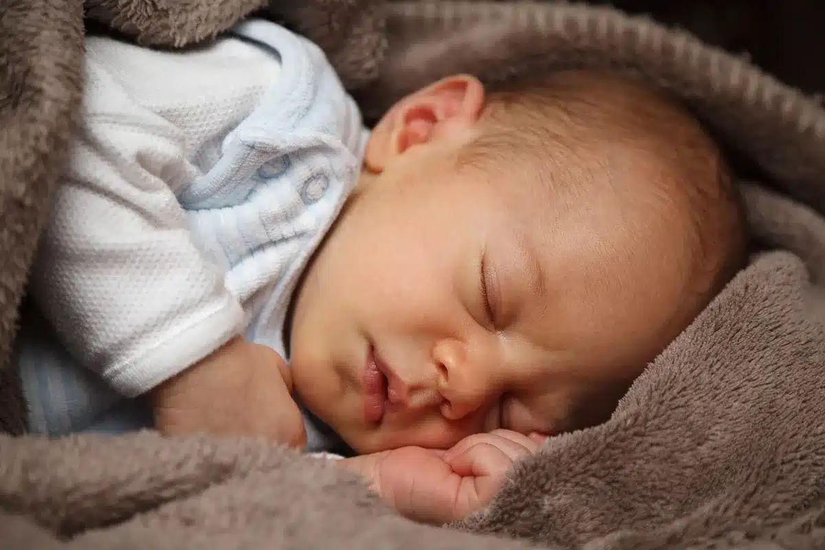 Main d'un parent appliquant une crème émolliente sur la peau d'un bébé