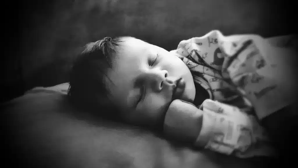 Personne endormie dans un lit, la nuit, avec des formes abstraites évoquant des rêves