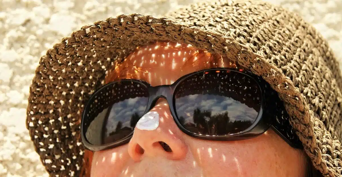 Femme appliquant de la crème solaire et portant des vêtements de protection contre le soleil