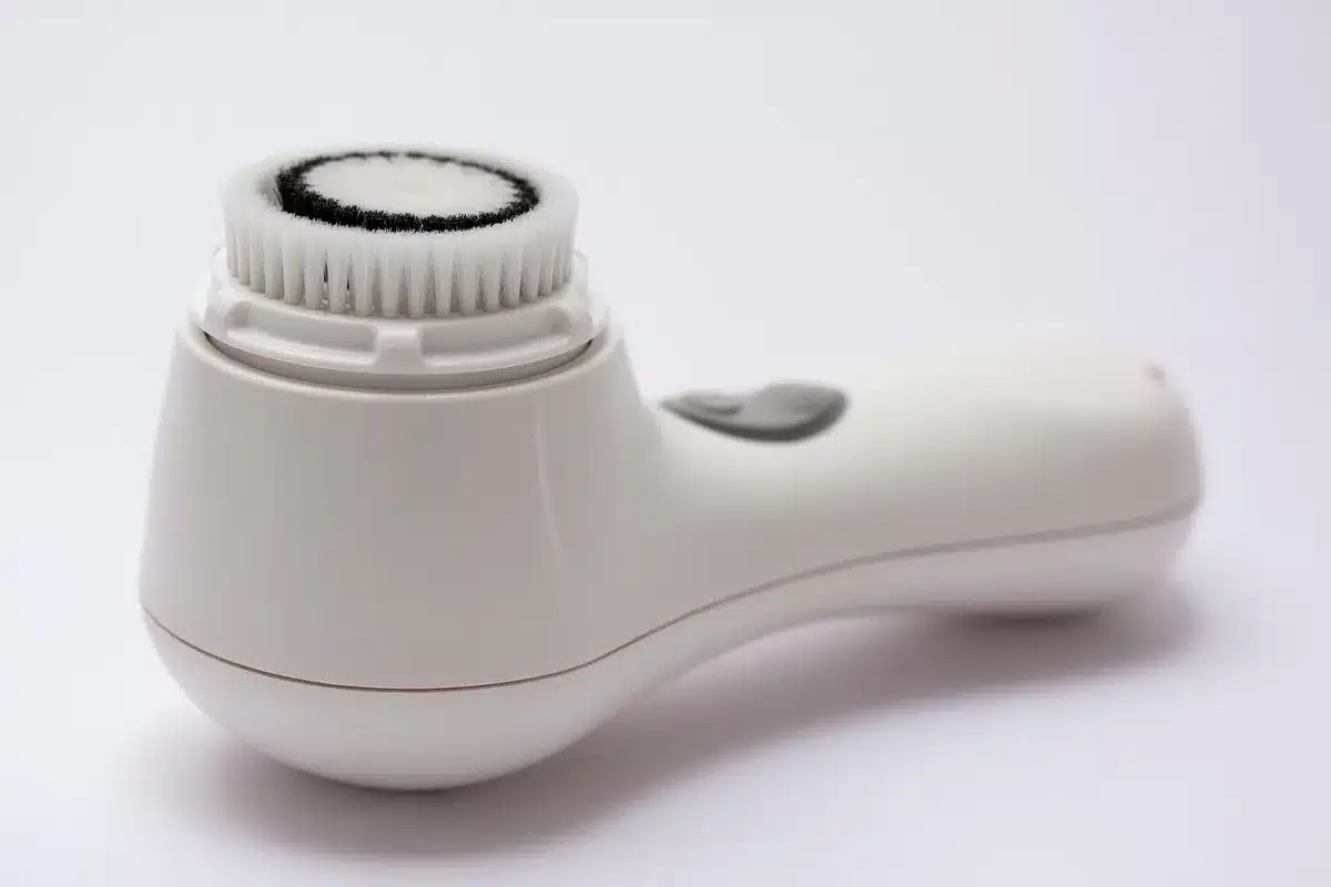 Mains appliquant un nettoyant doux sur un visage humide