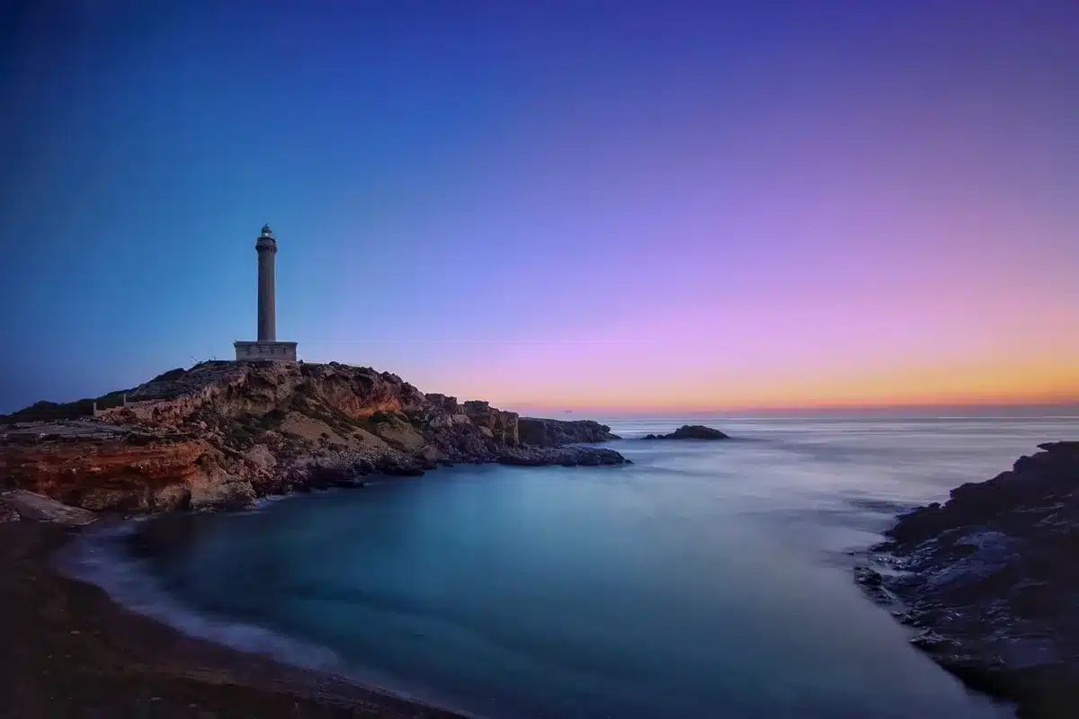 Chemin côtier en plein jour sur une île bretonne avec phare au loin