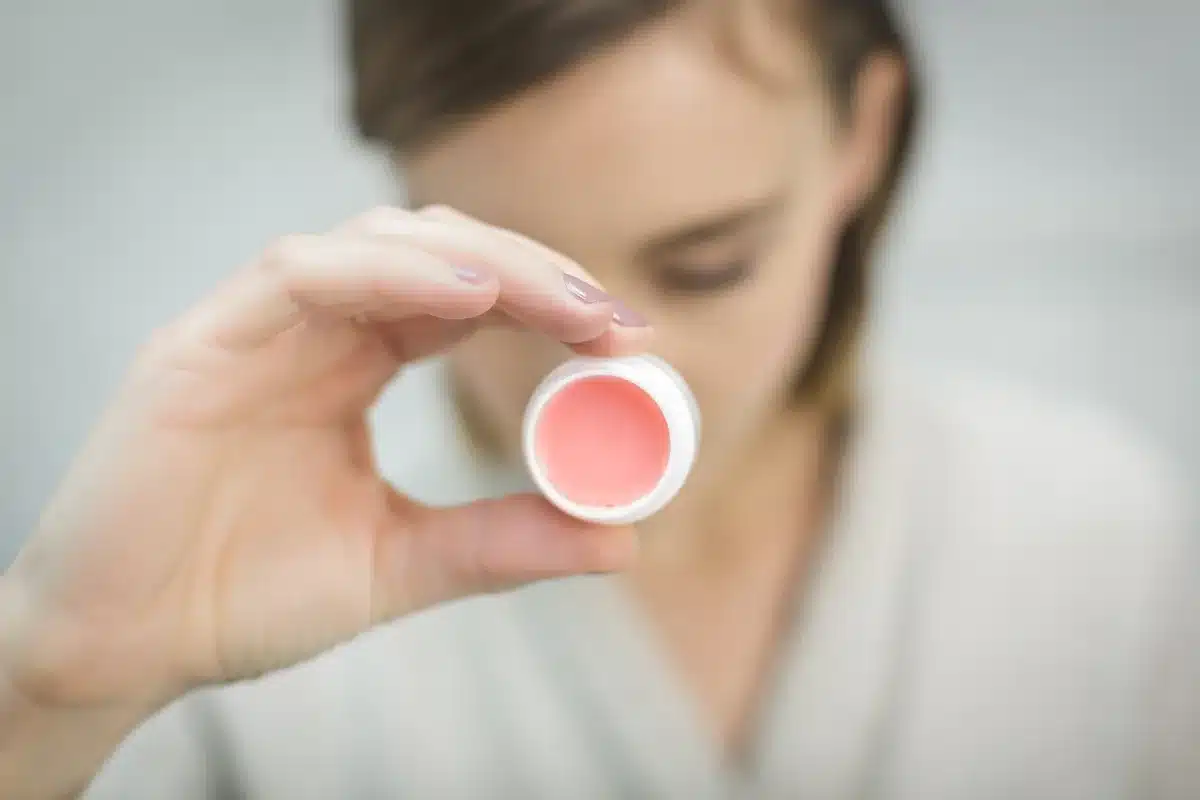 Personne nettoyant son visage sur un lavabo lumineux avec produits de soin