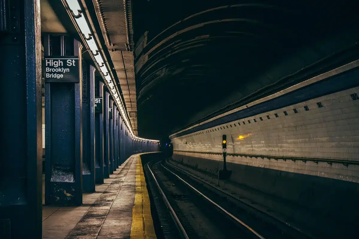 Voyageur avec vélo devant une gare belge en journée, prêt à partir